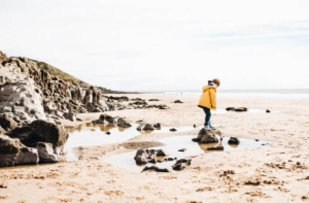 Child playing in the rockpools on the beach